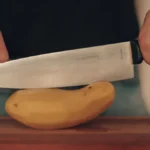 Kés és félbevágott nyers krumpli egy vágódeszkán