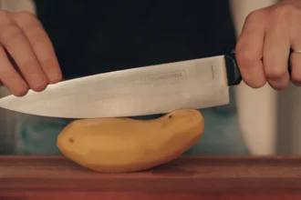 Kés és félbevágott nyers krumpli egy vágódeszkán