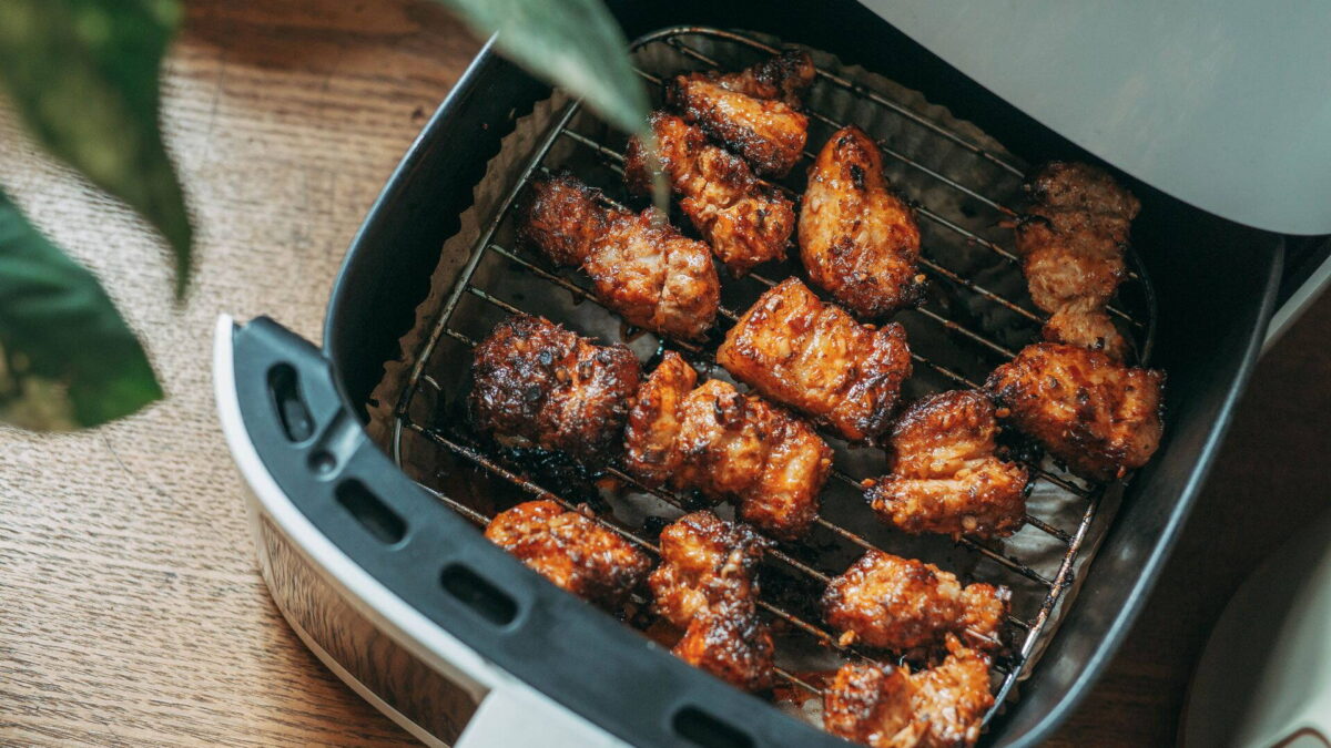 Air fryer kihúzott kosara rácson sült csirkedarabokkal