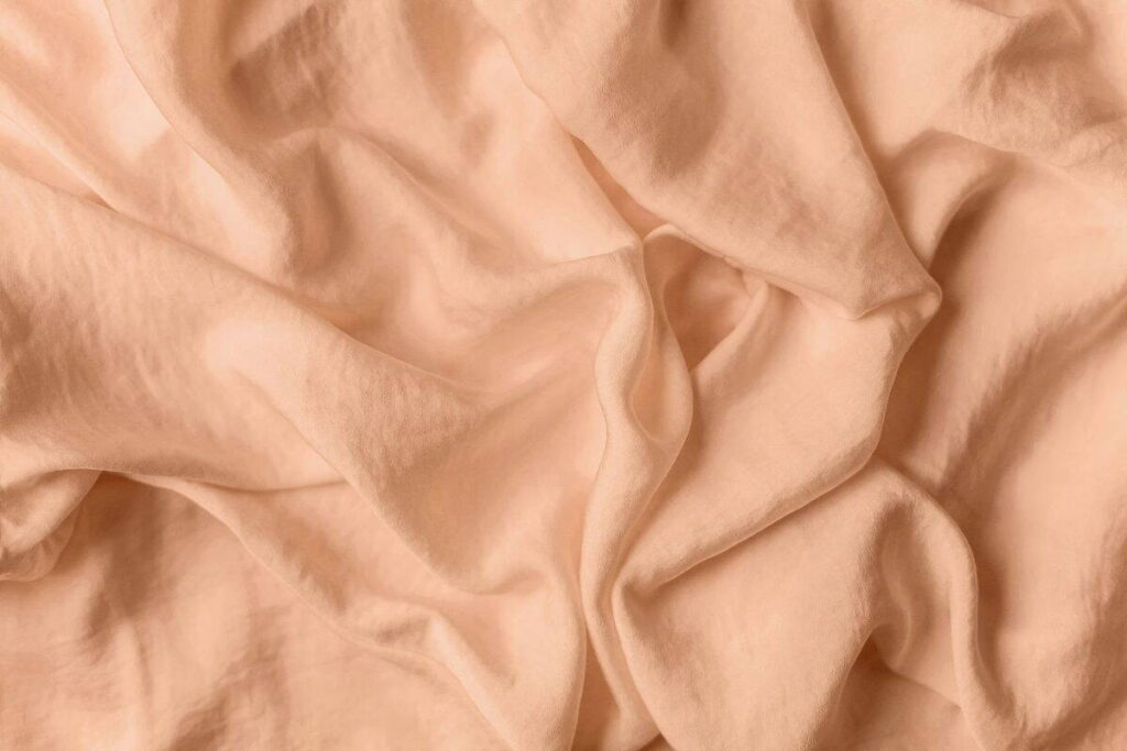 Gyűrött barackszínű textil közelről