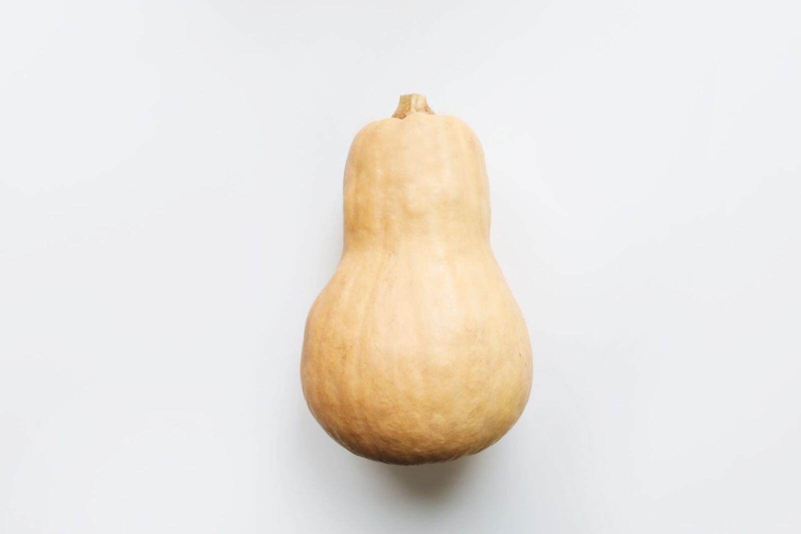 Egész butternut tök fehér háttér előtt