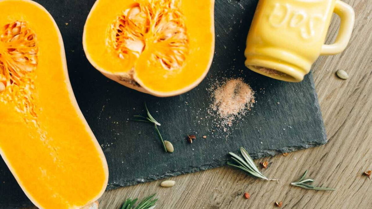 Félbevágott butternut tök fűszerekkel egy vágódeszkán
