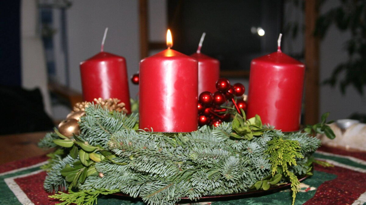 Fenyőágas adventi koszorú, rajta az első égő gyertyával